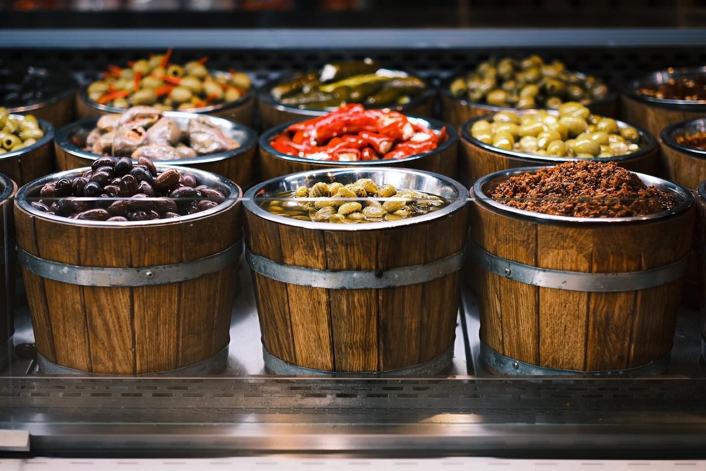 Drewniane beczki z różnymi oliwkami i antipasti na stoisku jarmarcznym — oferta hurtowa YEMEK