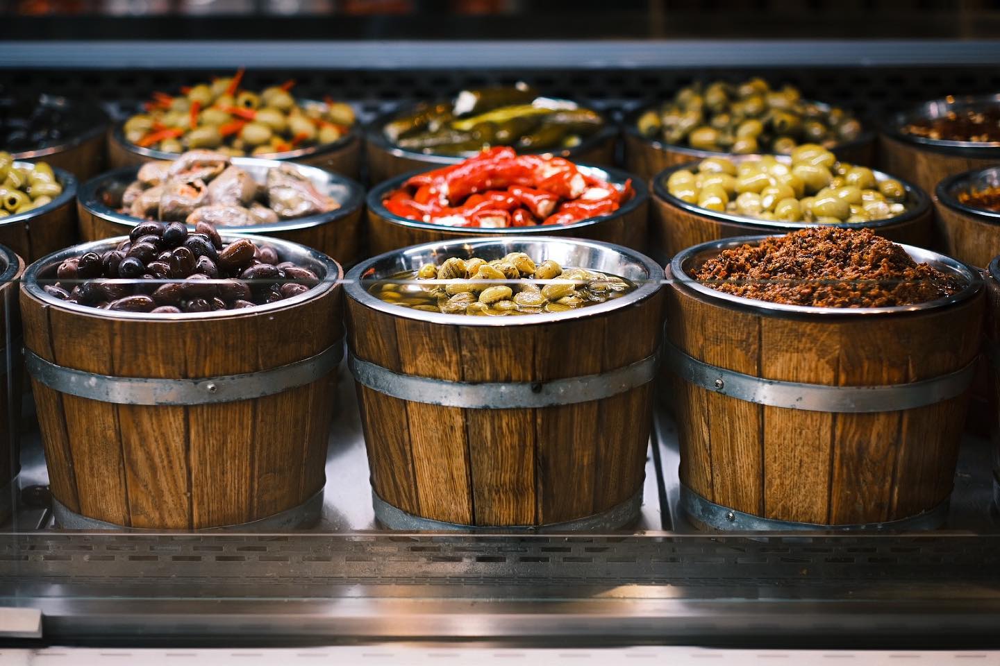 Drewniane beczki z różnymi oliwkami i antipasti na stoisku jarmarcznym — oferta hurtowa YEMEK